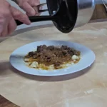 pouring beef in wine sauce onto mashed potatoes
