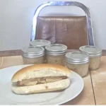 Hotdog with Dijon Mustard in front of jars of mustard