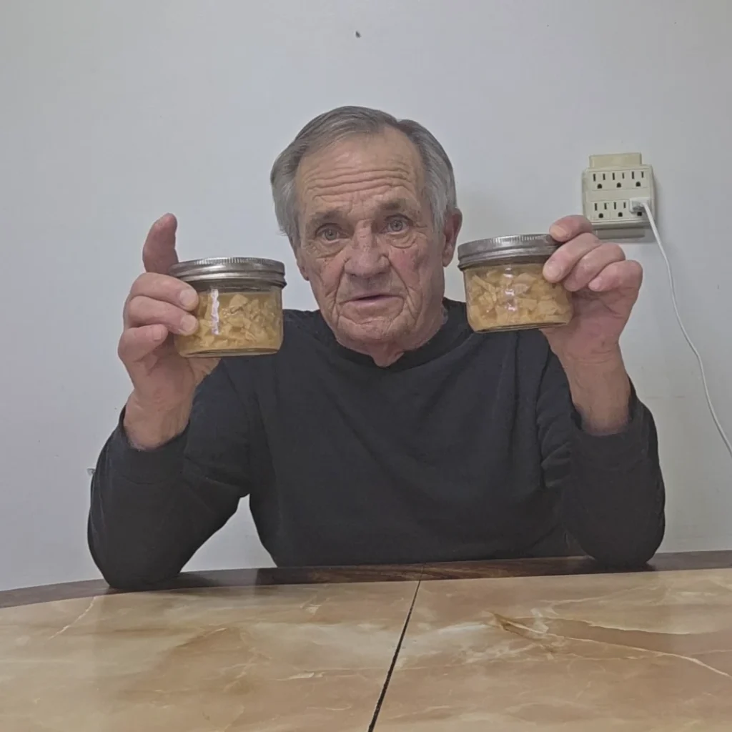 Sitting at he table holding 2 jars of canned turkey