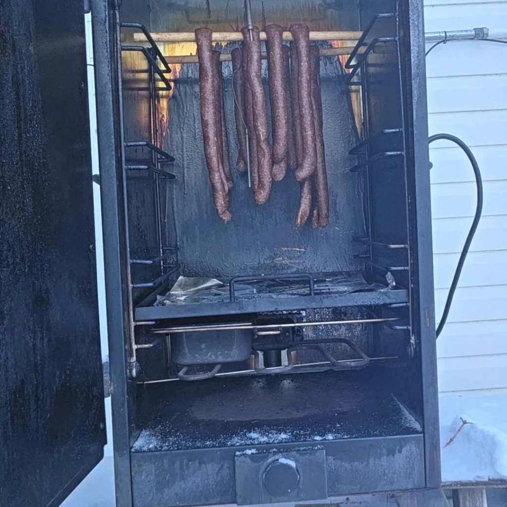 Pepperonis hanging in the smoker