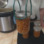 Pulling a jar of beans from the canner