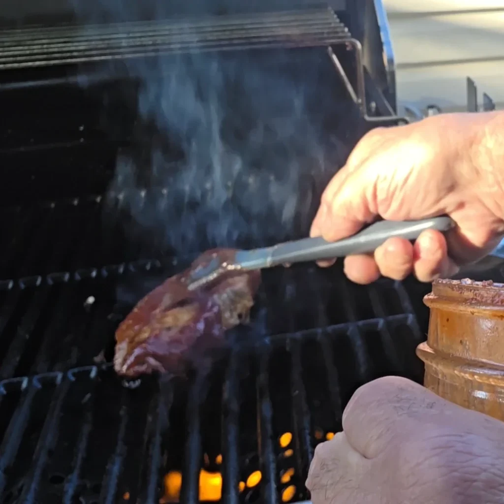 Brushing  sauce on a pork chop on the BBQ