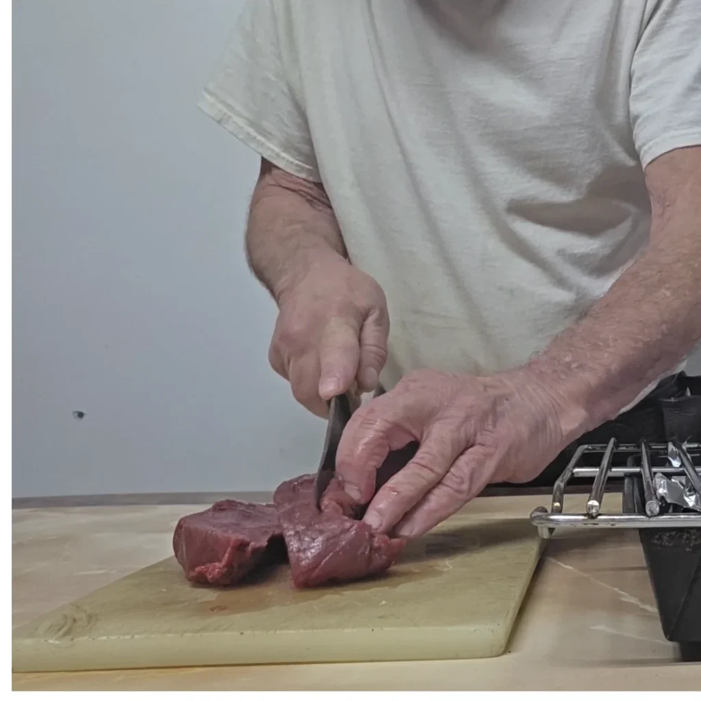 Slicing moose into 1 inch strips to cook in the oven